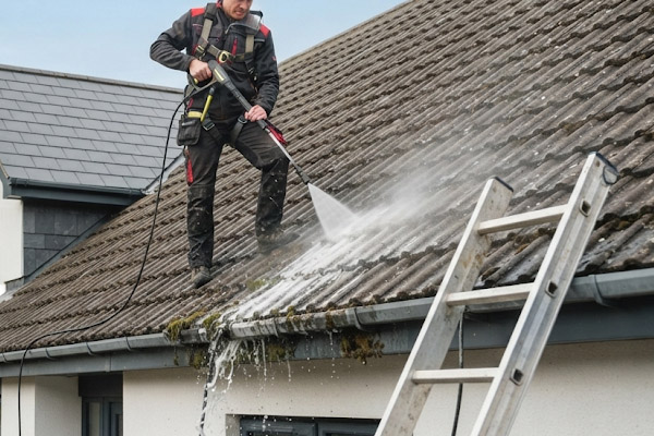 Couvreur faisant du démoussage sur une toiture